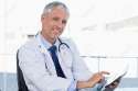 13607191-Smiling-doctor-working-with-a-tablet-computer-in-his-office-Stock-Photo.jpg