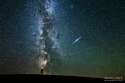 A person pointing towards an Iridium Flare, a reflection of sunlight across a satellite in space. The Milky Way is clearly visible in the background.jpg
