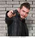 stock-photo-mad-man-pointing-with-gun-against-a-brick-wall-120795139.jpg