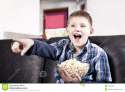ragazzo-felice-biondo-che-guarda-tv-e-che-mangia-popcorn-24012468.jpg