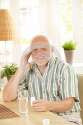 smiling-senior-holding-medication-sitting-table-home-looking-camera-33471662.jpg